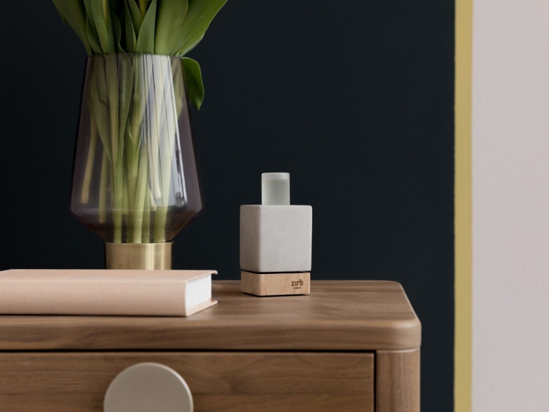 Das Einsteigermodell zirb.Mini fügt sich dezent in die Wohnung ein Das edle Design von zirb.Mini aus Beton und Holz fügt sich dezent auf der Holz-Kommode neben dem Buch und der Blumenvase ein