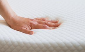 Eine Hand drückt auf eine Matratze und prüft, wie elastisch sie noch ist